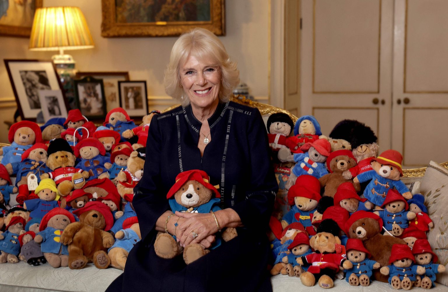 TOPSHOT - A Buckingham Palace handout image released on October 16, 2022, shows Britain's Camilla, Queen Consort posing with a collection of Paddington teddy bears in the Morning Room at the Clarence House, in London, on the 64th anniversary of the publication of the first Paddington bear book, on October 13, 2022. - More than 1,000 Paddingtons and other teddy bears left by mourners following Queen Elizabeth II's death are being donated to a leading children's charity, Buckingham Palace said October 15, 2022. Barnardo's will receive the professionally cleaned toys in the coming weeks after they were left outside royal residences in London and Windsor, along with a sea of flowers, after Elizabeth died on September 8. (Photo by CHRIS JACKSON / BUCKINGHAM PALACE / AFP) / RESTRICTED TO EDITORIAL USE - MANDATORY CREDIT "AFP PHOTO / HO / Buckingham Palace / CHRIS JACKSON / GETTY IMAGES" - NO MARKETING NO ADVERTISING CAMPAIGNS - DISTRIBUTED AS A SERVICE TO CLIENTS -  THE PHOTOGRAPH SHALL NOT BE USED AFTER OCTOBER 30th 2022. /