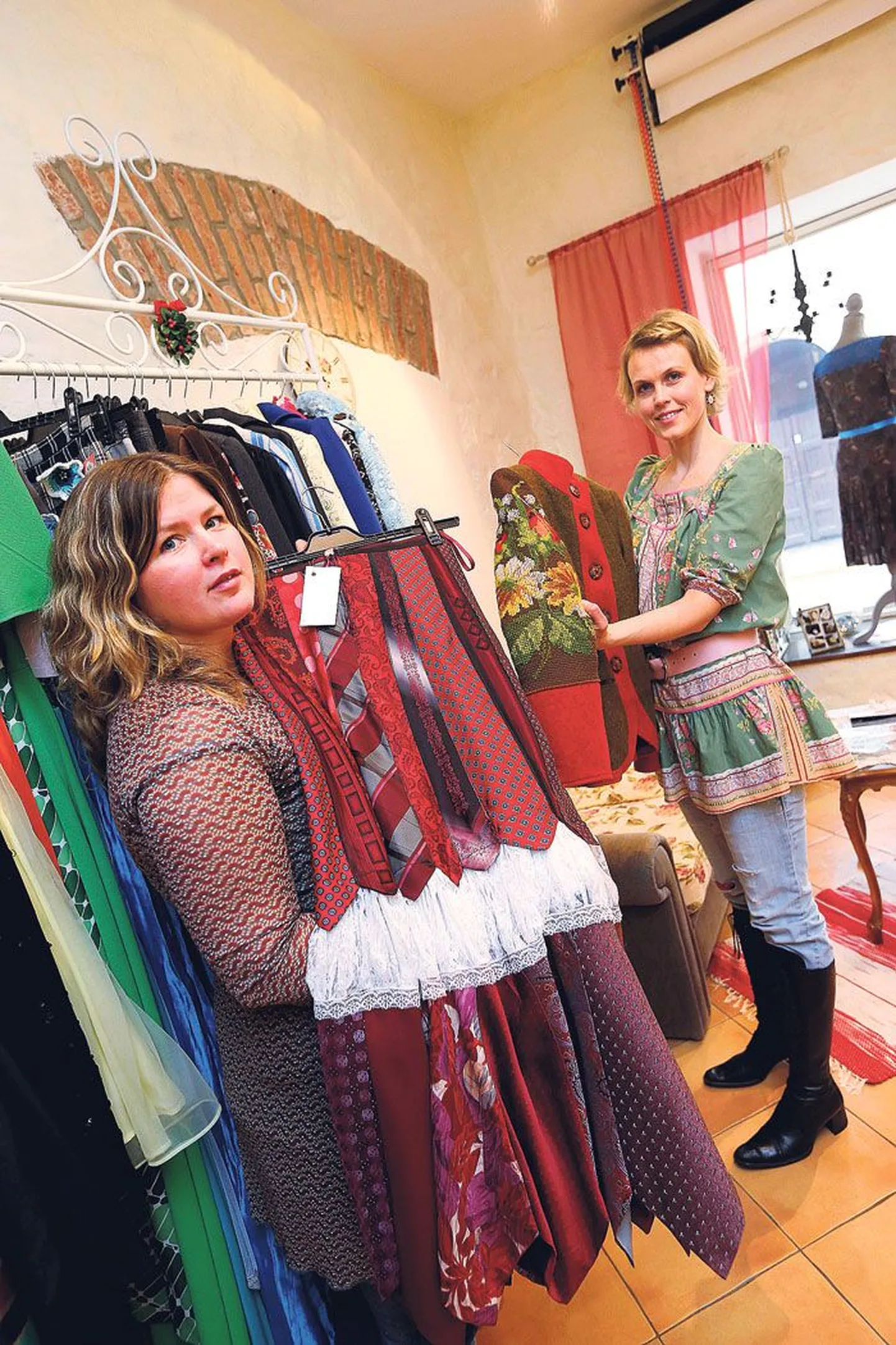 Marika Normet (vasakul) ja Helina Saar näitavad oma õmblussalongis valminud kantud lipsudest seelikut ja vana tikitud seinapildiga täiendatud jakki, mis sai moodsama lõike.