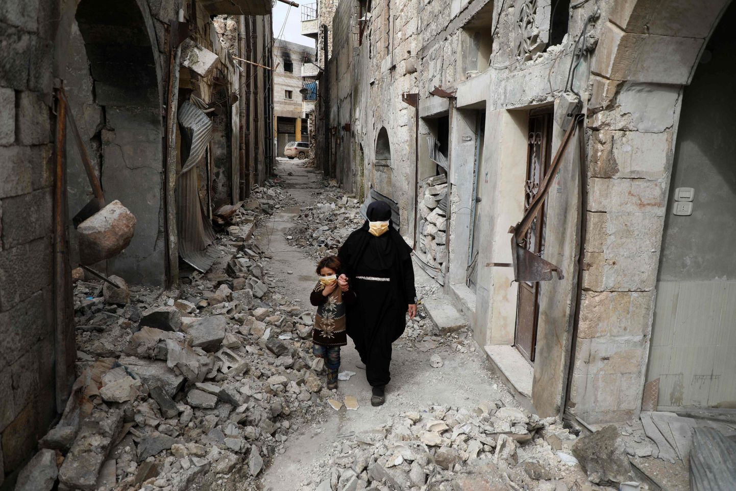 Sīriete ar meitu iet cauri sagrautajām ielām Idlibas provincē.