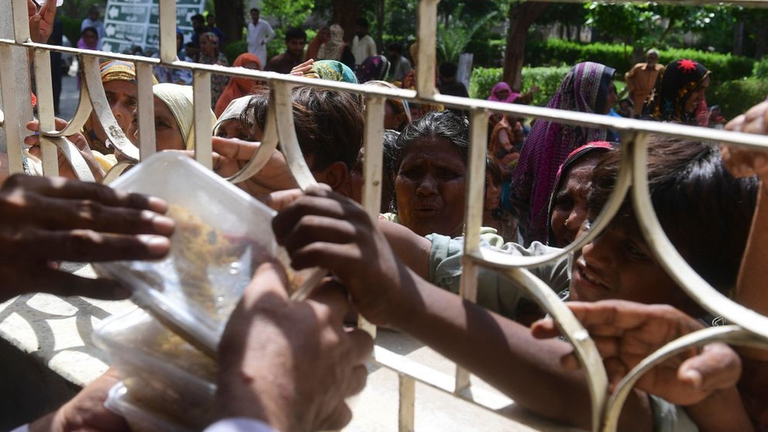 Беженцы дерутся, чтобы получить порцию еды от правительственного чиновника в Суккуре, провинция Синд, 29 августа 2022 года