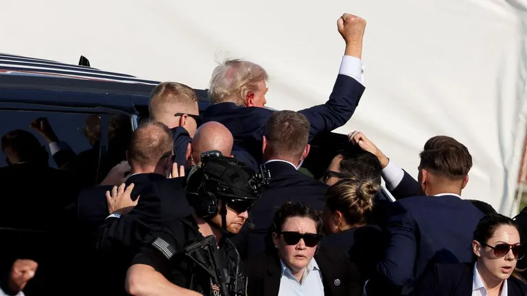 Трампа сажают в машину.