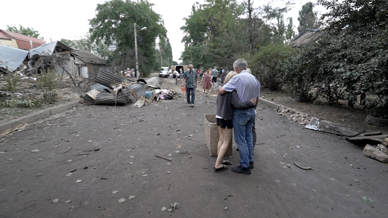 Жители утешают друг друга посреди развалин на городской улице