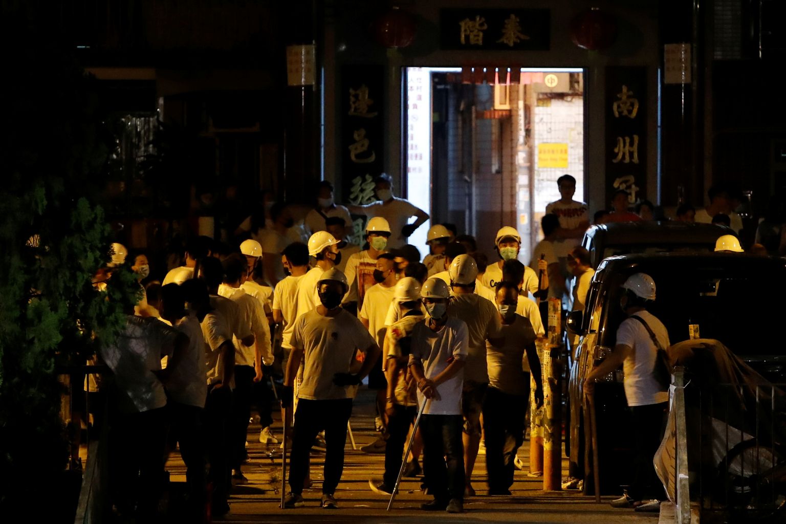 Kurikate ja metalltorudega relvastatud valgetes särkides mehed Yuen Longi metroojaama juures.