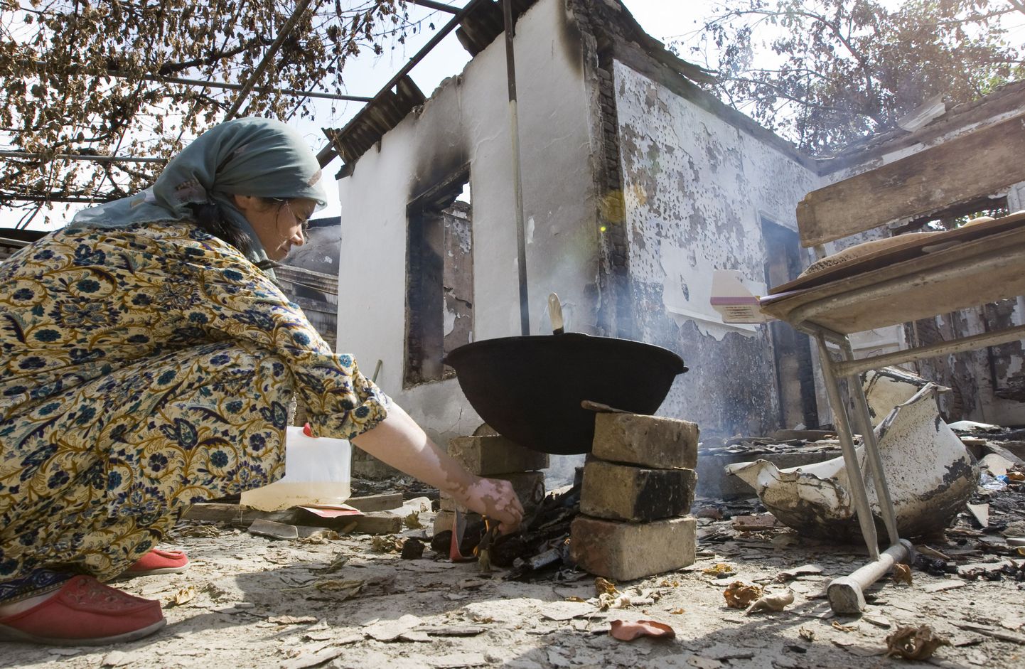 Kõrgõzstanis Ošis elav usbeki naine keedab oma kodumaja varemete juures süüa.