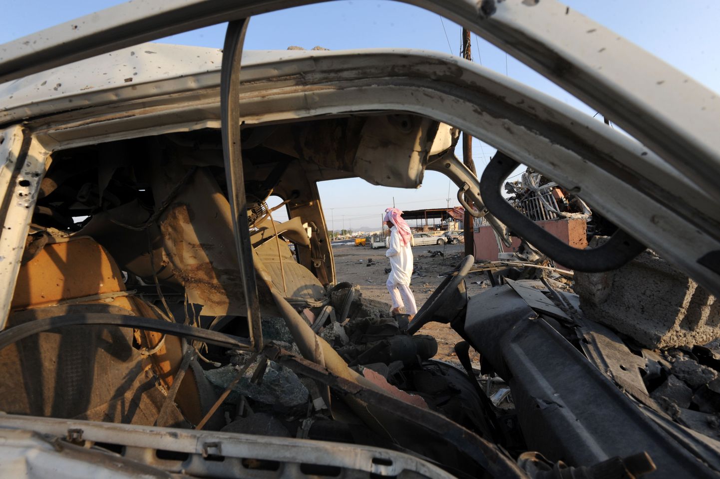 Saudi mees kõnnib mööda Jeemenist tulistatud raketitules hävinud sõidukist.