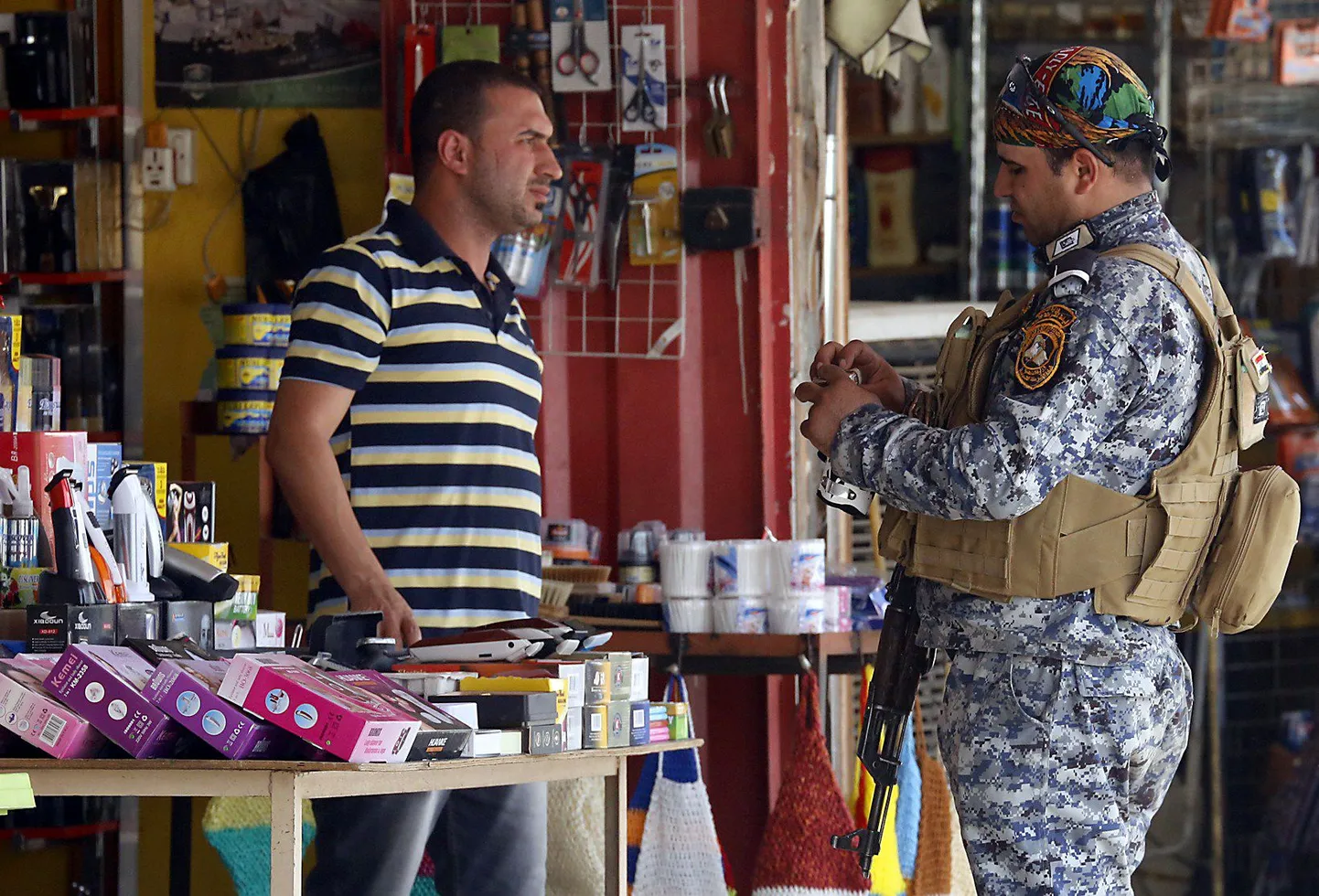 A member of the Iraqi security forces check an item at a shop in central Baghdad on June 19, 2014, as fighting reaches the northern approaches to the Iraqi capital following a lightning assault launched by Sunni Muslim insurgents on June 9 in which they have captured Mosul, a city of two million people, and a big chunk of mainly Sunni Arab territory stretching south towards Baghdad. AFP PHOTO/SABAH ARAR