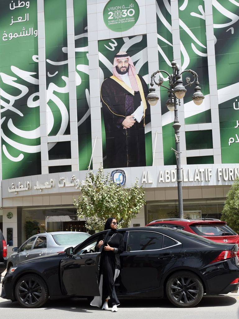 Plakat kroonprints Mohammed bin Salmanist ja naine, kes alles sel suvel sai riigis õiguse autot juhtida.