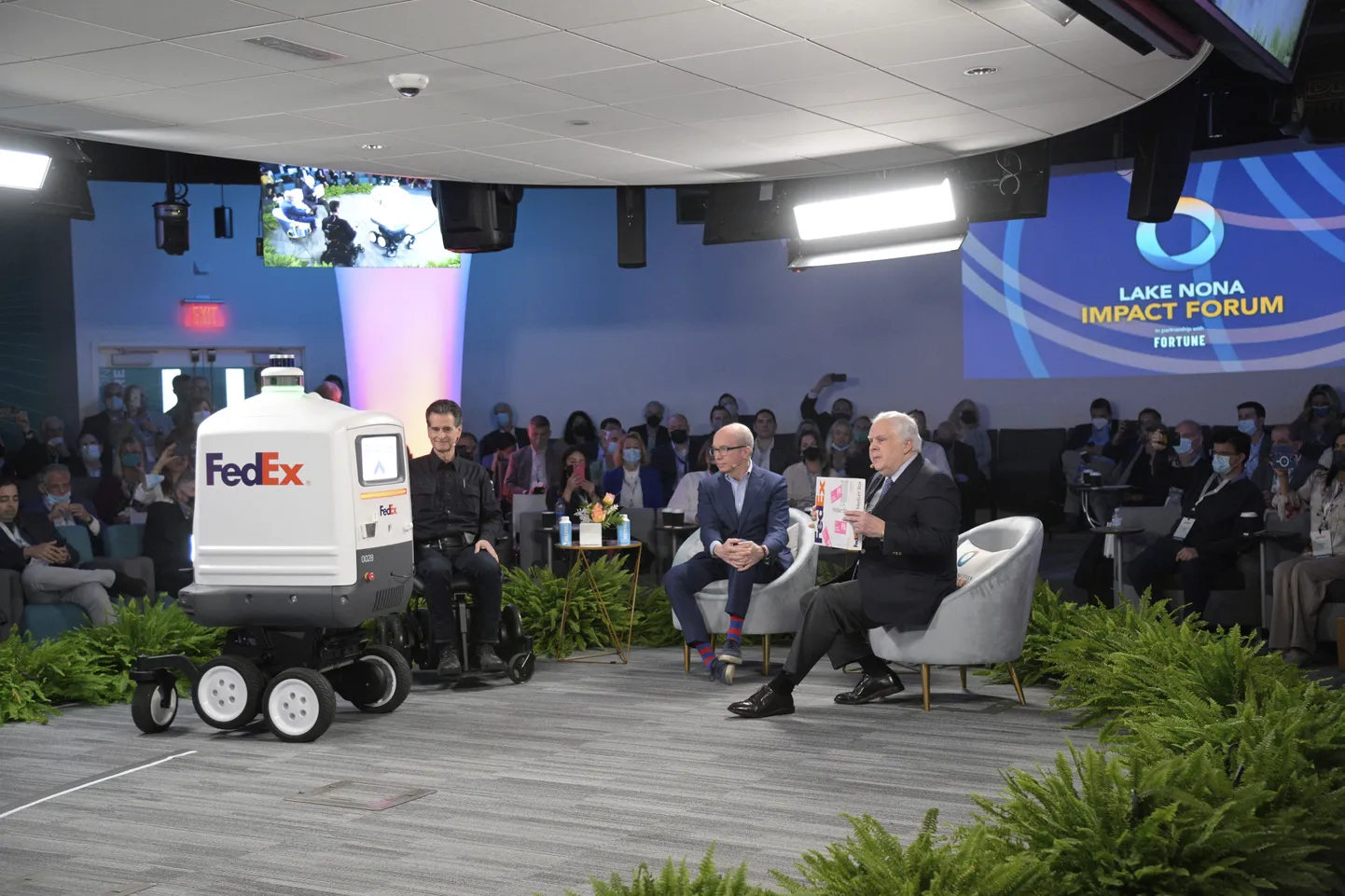 Robot Roxo toimetamas pakikest FedExi asutajale, esimehele ja tegevjuhile Frederick W. Smithile (paremal) suurel meediaüritusel Orlandos 24. veebruaril 2022.