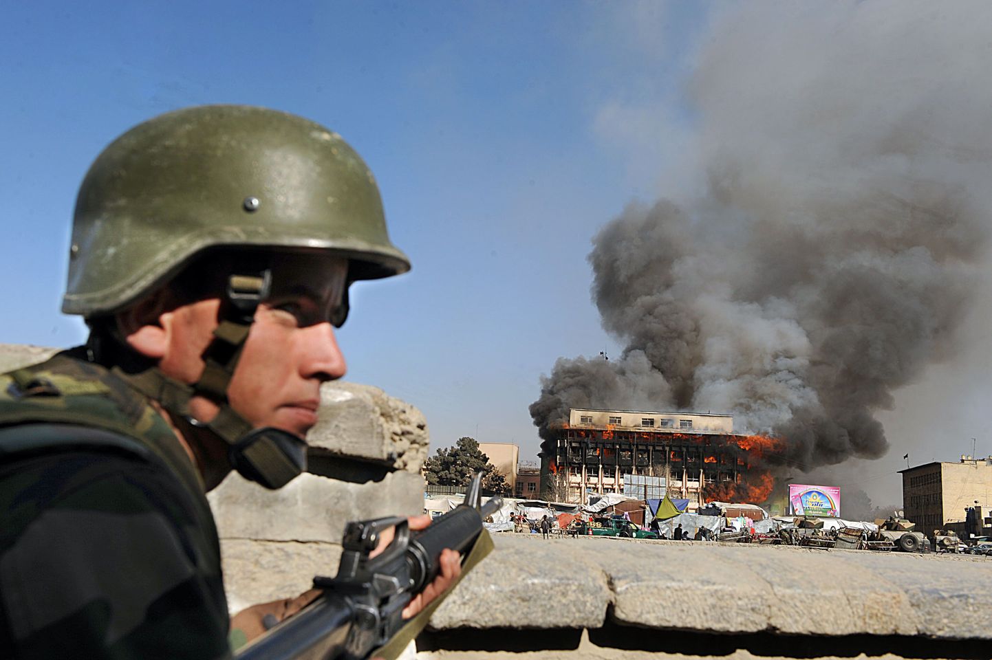 Afgaani sõdur valvamas põleva hoone juures.
