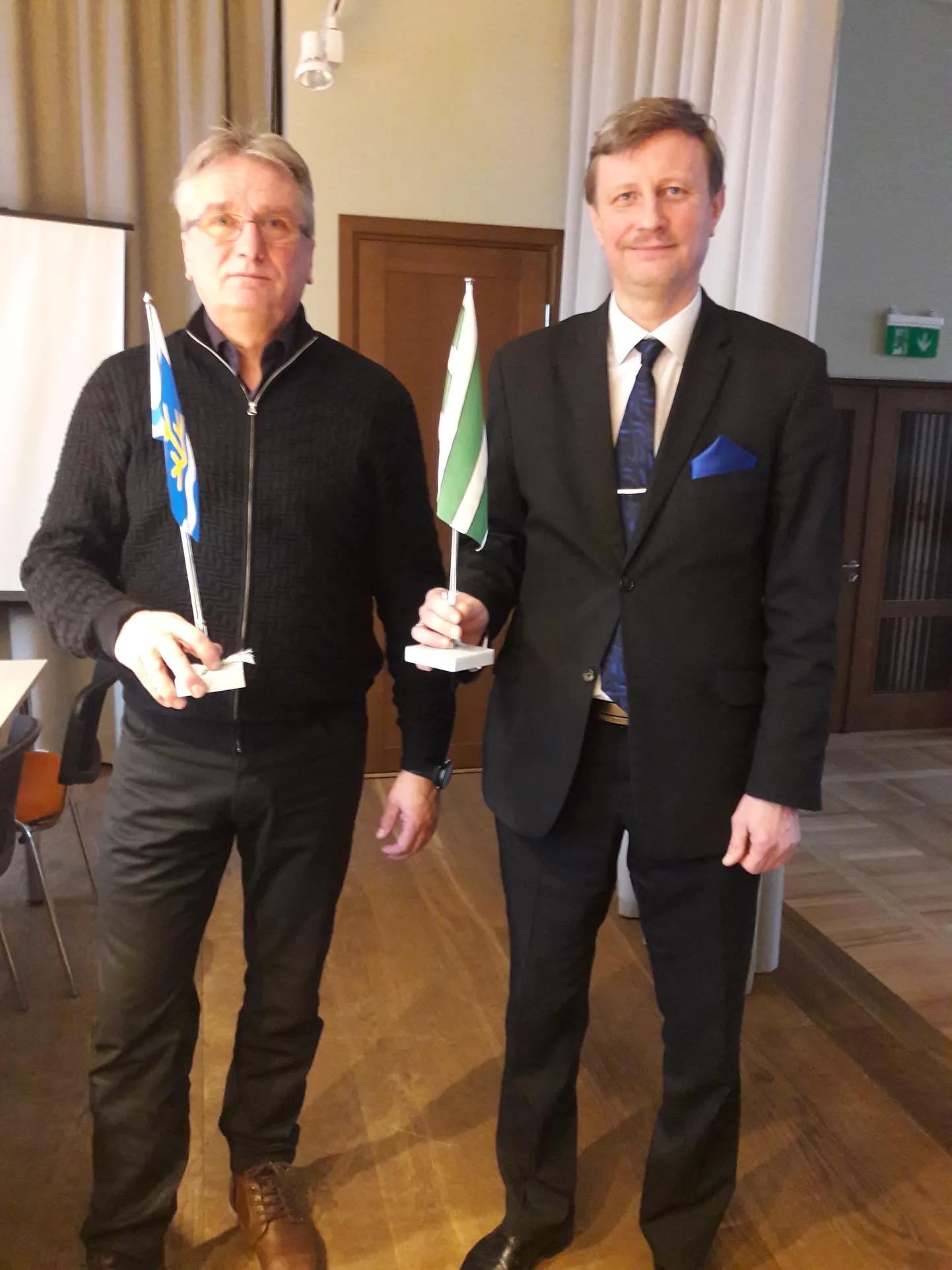 Jõhvi volikogu esimees Eduard East (paremal) ning Toila volikogu esimees Roland Peets poseerimas Põhjarannikule oma valla lipuga. See lõppes Toila lipu kinkimisega Jõhvi vallale. "Meil on siin igasuguseid lippe, isegi Hiina lipp, kuid Toila oma seni polnud," sõnas Eduard East.