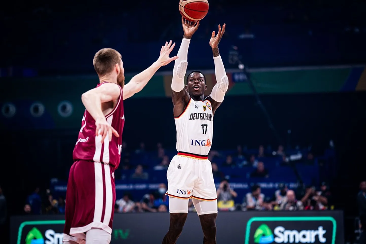 Vācijas basketbolists Deniss Šrēders izpilda metienu pāri Dāvja Bertāna rokām
