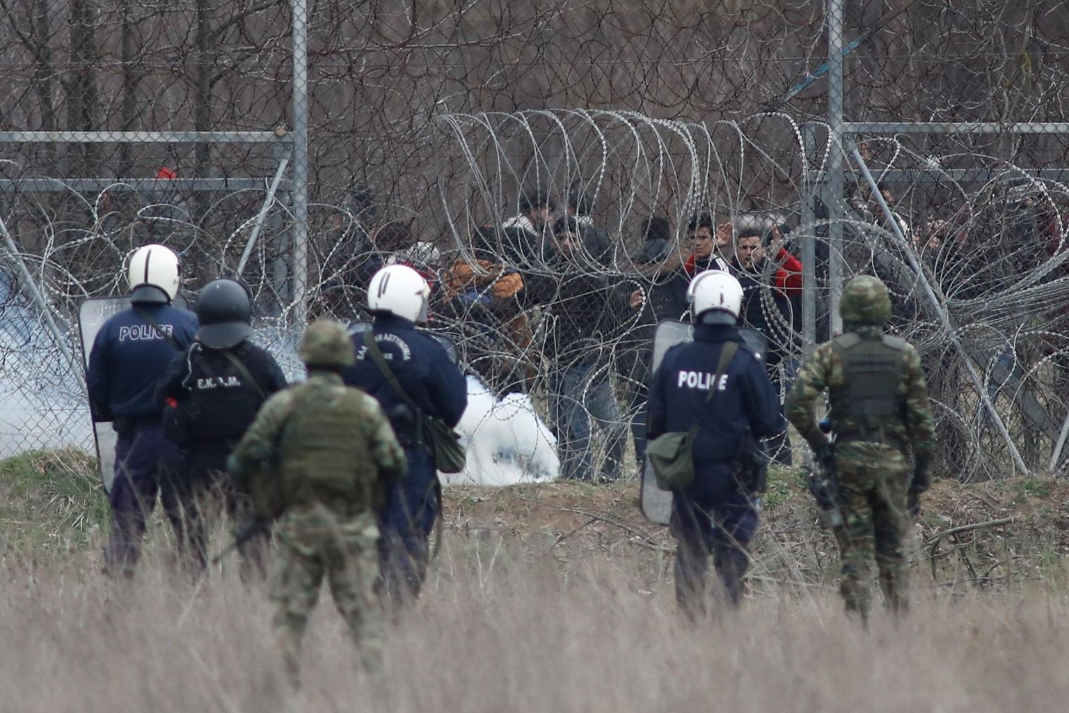 Pagulased üritavad Kreeka politseinike ja kaitseväelaste pilgu all Kreeka-Türgi piiril Kastaniési lähedal traattõkkest läbi tungida.
