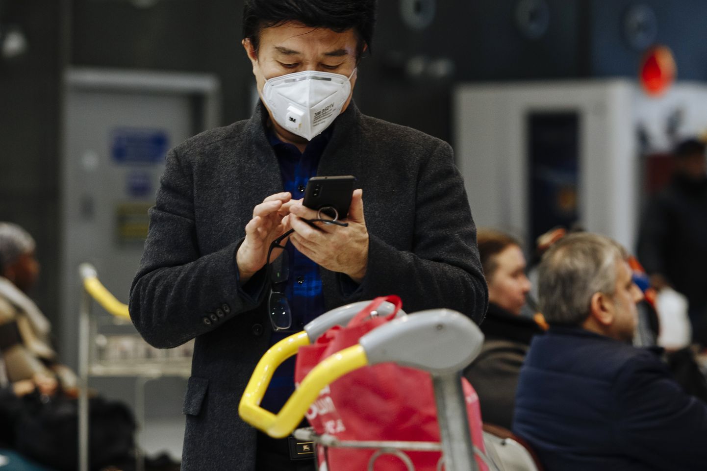 A traveler from Beijing, wearing a mask, uses his cellphone as he arrives at Charles de Gaulle airport, north of Paris, early Monday, Jan. 27, 2020. France's government announced Sunday it will repatriate up to hundreds of French citizens from the Chinese city of Wuhan, the epicenter of a deadly new virus. (AP Photo/Kamil Zihnioglu)