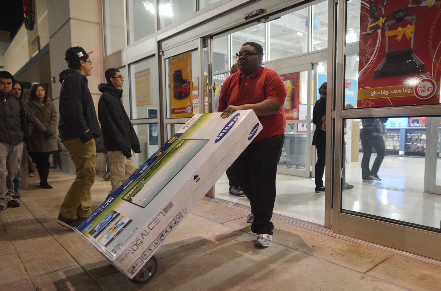 An employee wheels out a large TV newly purchased from a hh Gregg electronics store which began their Black Friday sales before midnight November 22, 2012 in Rockville, Maryland.   Thanksgiving, the last US holiday undisturbed by mass commercialization, is now victim to the ever advancing Christmas shopping season, with stores welcoming shopaholics before the family turkey can be taken from the oven.  AFP PHOTO / Mandel NGAN