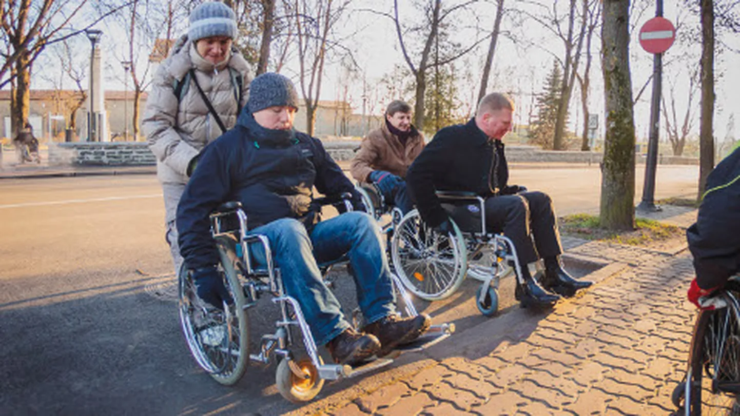 Üritusest "Üks tund inimese elust ratastoolis" osavõtnud ei pääsenud üle linnavalitsuse hoone juures oleva kõnnitee äärekivide. Fotol ratastoolides Narva linnavolikogu liige Ants Kutti, linnapea Eduard East (tagaplaanil) ja linnavolikogu aseesimees Aleksandr Jefimov. Linnaisadel aitab oma "baasi" naasta Margarita Semjonova Narva füüsiliste puuetega inimeste ühingust Sportuna.