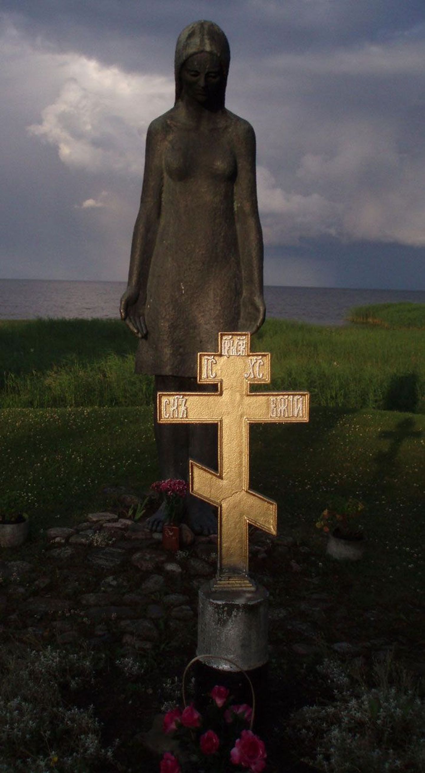 Скорбящая дева на берегу Чудского озера поставлена над братской могилой, в которой покоятся воины, погибшие во время Второй мировой, а православный крест обозначает, что это место —  первое старообрядческое кладбище.