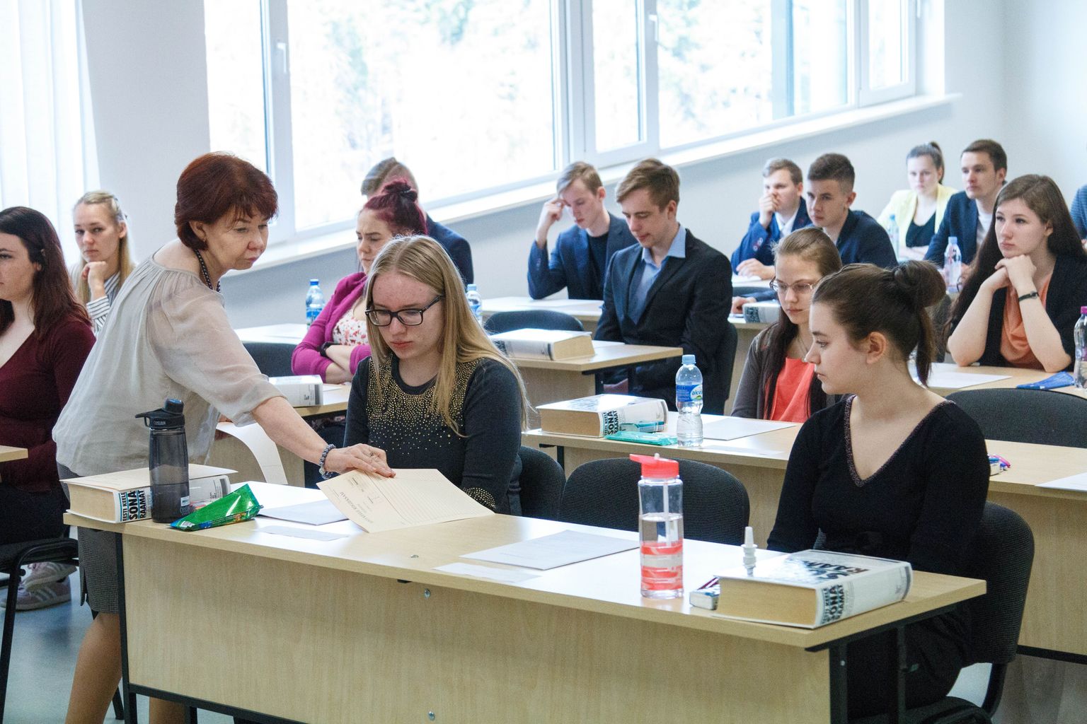 Eesti keele õpetaja Riina Anderson jagamas õpilastele mustandipabereid.