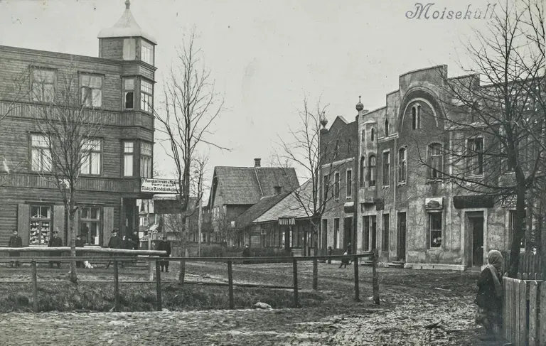 Как в большом городе: Мыйзакюла в 1913-1914 гг., угол улиц Кеск и Пости. Здание слева, в котором располагалось несколько предприятий, в том числе фотоателье Ричарда Эмиля Якобсона и его книжный магазин, а также магазин модной одежды, сгорело со многими соседними зданиями в крупном пожаре 26 июля 1915 года. Напротив него стоит жилой дом с коммерческими площадями Карла Кальценау (1913).