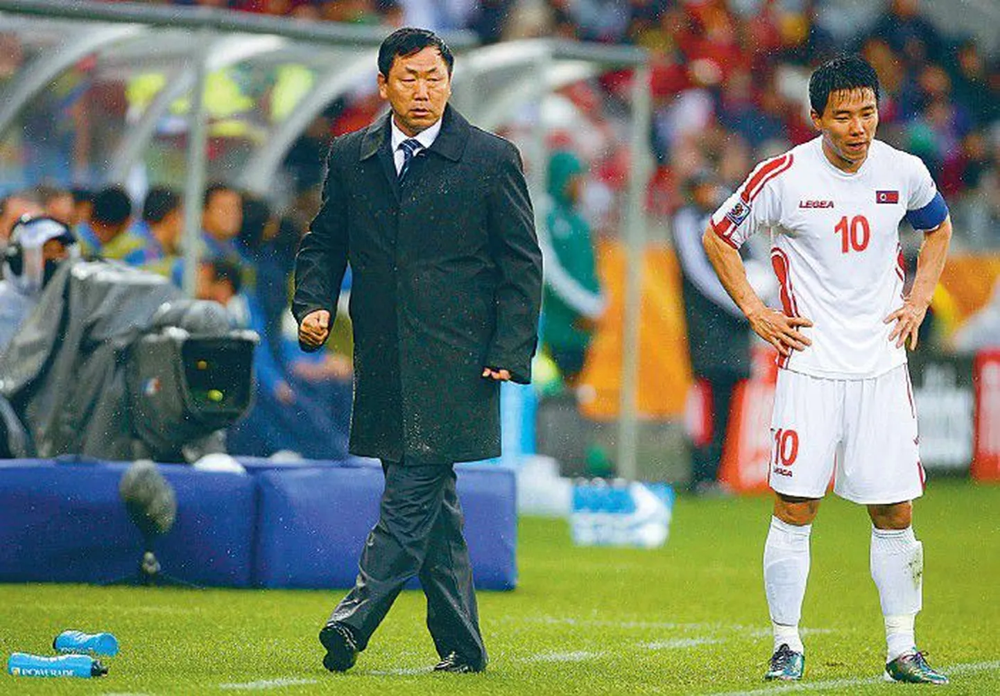 Главный тренер сборной КНДР по футболу Ким Чон Хун (слева) был сурово наказан за неудачное выступление команды.