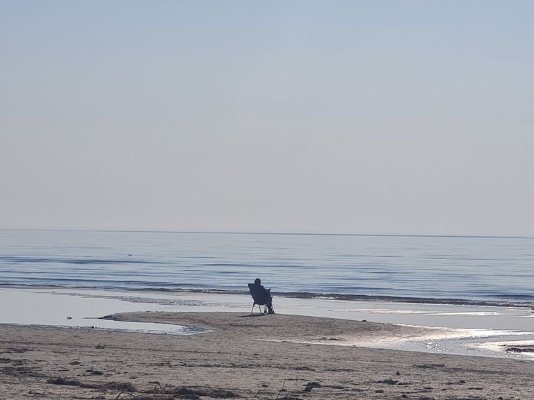 Человек на морском берегу в Лиепае. Пока не начат пляжный сезон, лиепайчане находят, как наслаждаться первыми лучами солнца. Главное - не сидеть дома. Апрель 2022 года