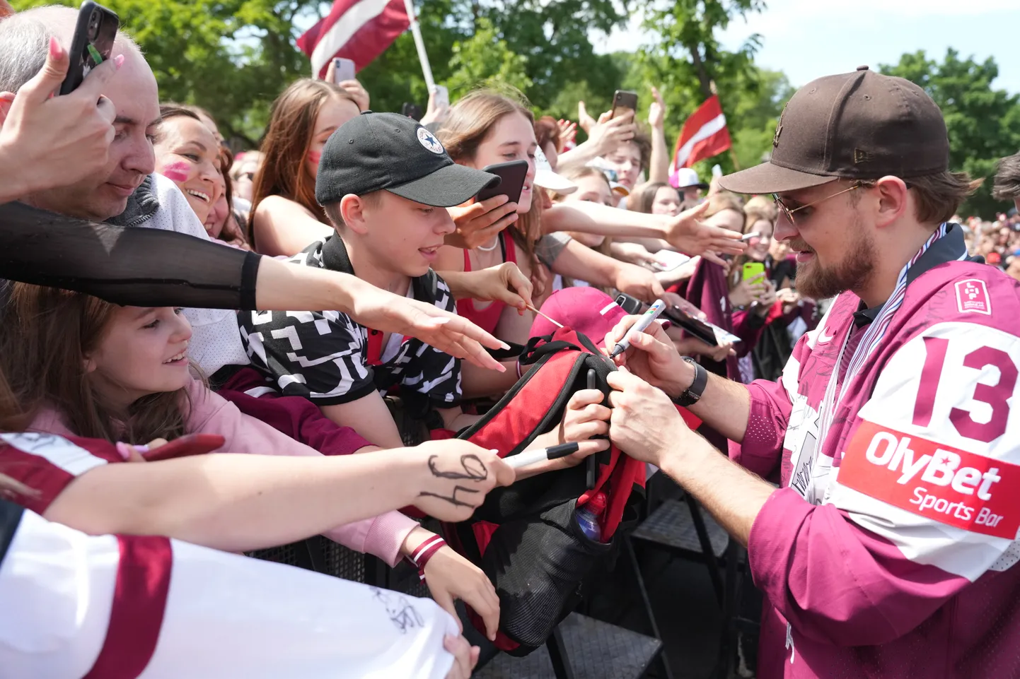 Latvijas hokeja izlases spēlētājs Rihards Bukarts sniedz autogrāfu pie Brīvības pieminekļa