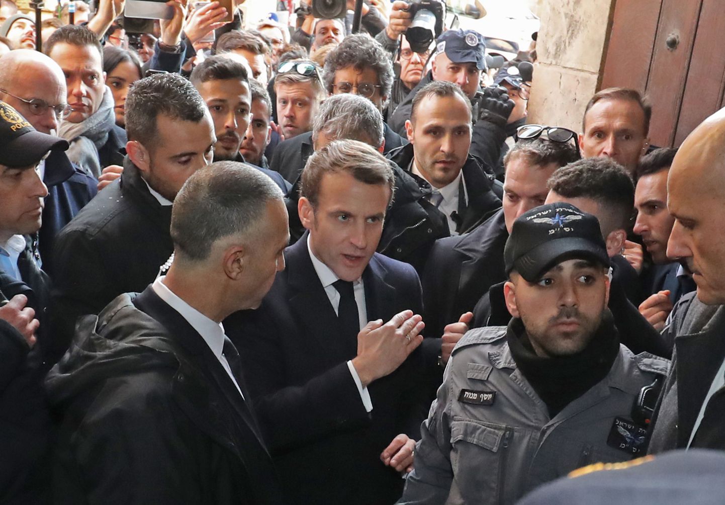 Prantsusmaa president Emmanuel Macron (keskel) sõnelemas eile Jeruusalemma Püha Anna kiriku uksel Iisraeli julgeolekutöötajatega.