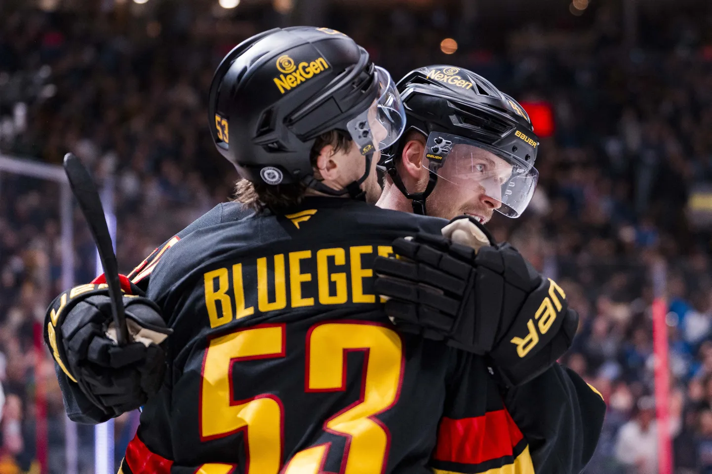 Vankūveras "Canucks" uzbrucējs Teodors Bļugers un uzbrucējs Eliass Pettersons svin Bļugera gūtos vārtus pret Minesotas "Wild"