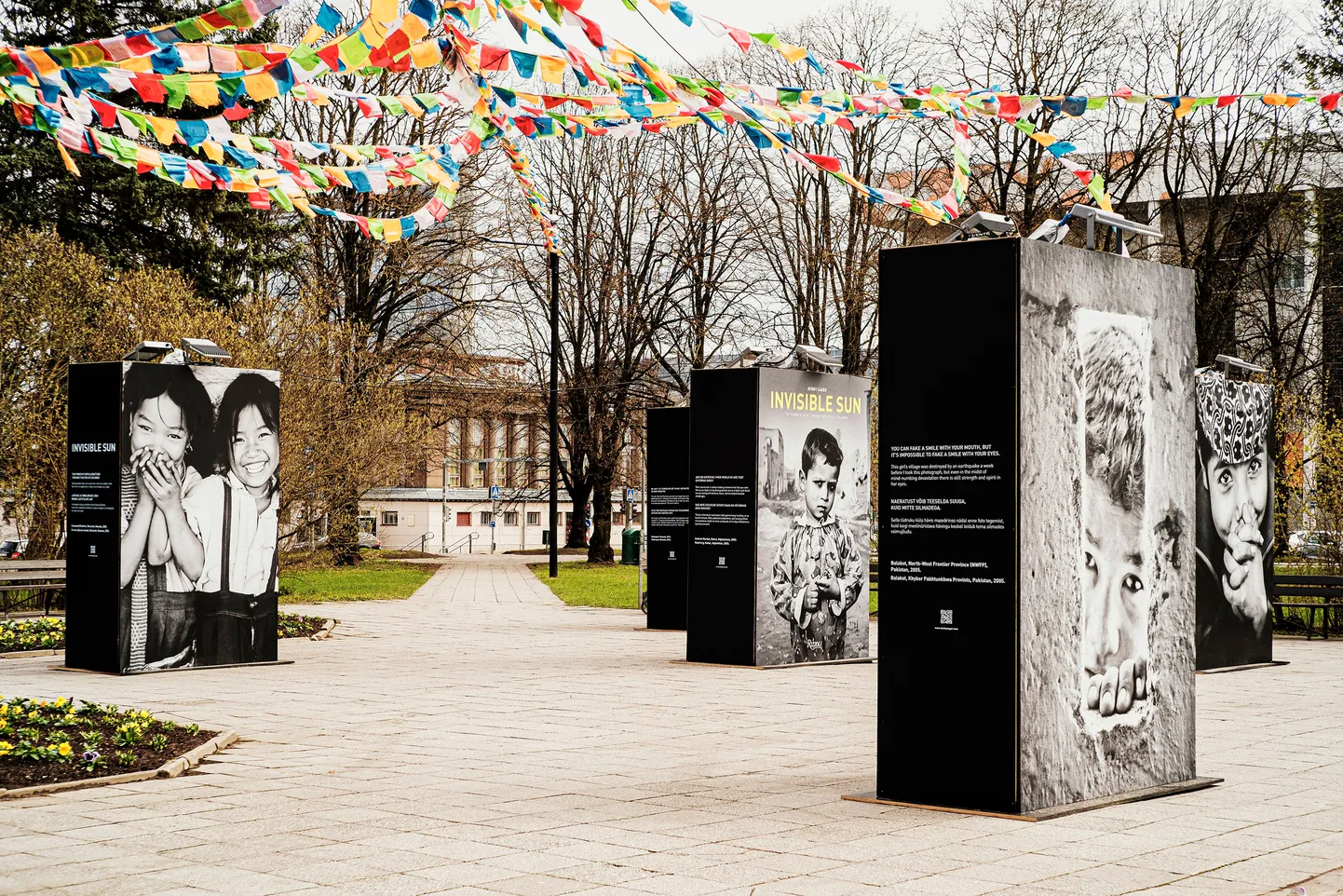 Tartu kesklinna pargis lehvivad näituse fotode ja tekstide kohal Tiibeti palvelipud.