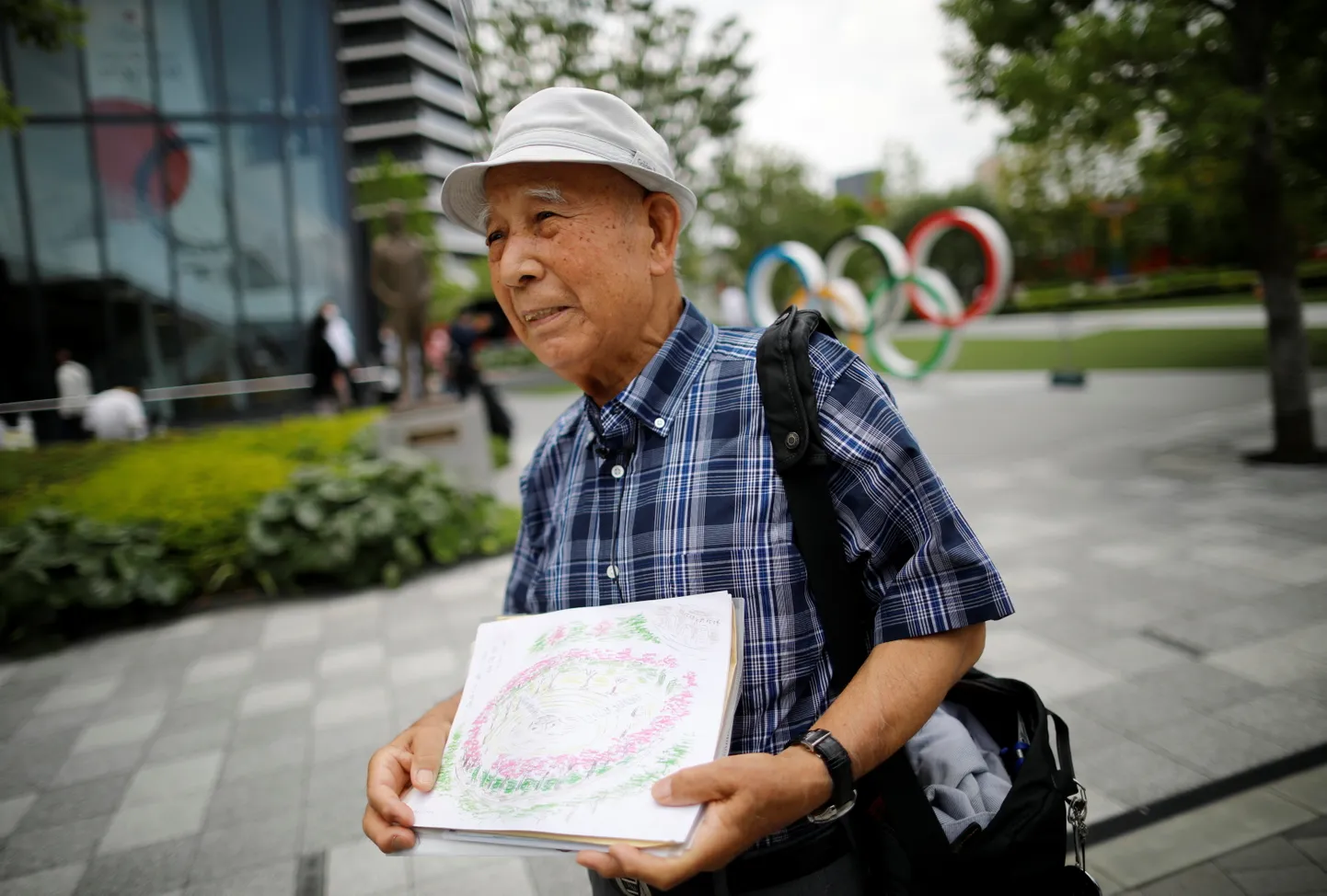 Nüüdseks 87-aastane Kohei Jinno kaotas kõigepealt kodu 1964. aasta Tokyo olümpia eel, kuna see jäi ette rahvusstaadioni rajamisele, ning peatselt algava olümpia tõttu lammutati ka maja, kus ta oli viimased pool sajandit elanud. Pildil Jinno rahvusstaadioni lähistel olümpiamuuseumi ees.
