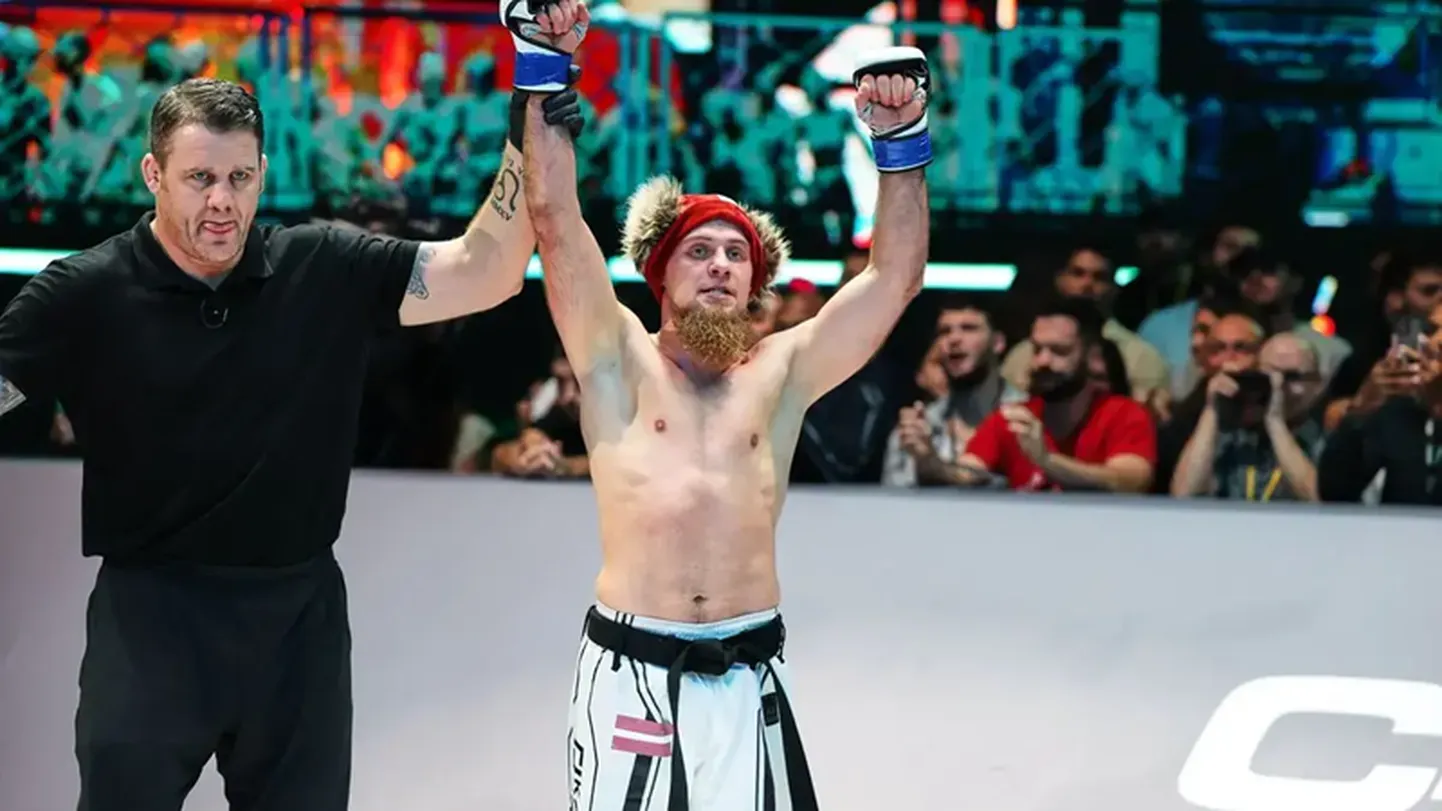 Edgars Skrīvers pēc uzvaras 2022. gadā. Viņam roku pacēlis viens no MMA slavenākajiem tiesnešiem Marks Godards.
