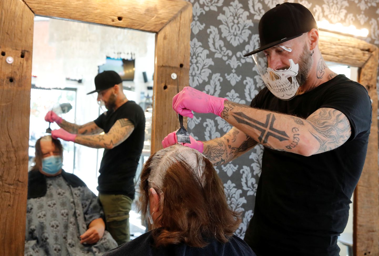 Šveitsis taasavati juuksurisalongid. Juuksur ja tema klient on kaitsemaskiga.