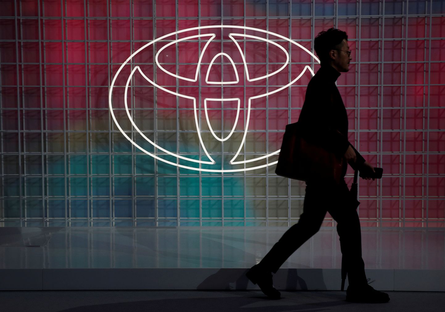 Mees kõndimas Tokyo autonäitusel Toyota logost mööda.