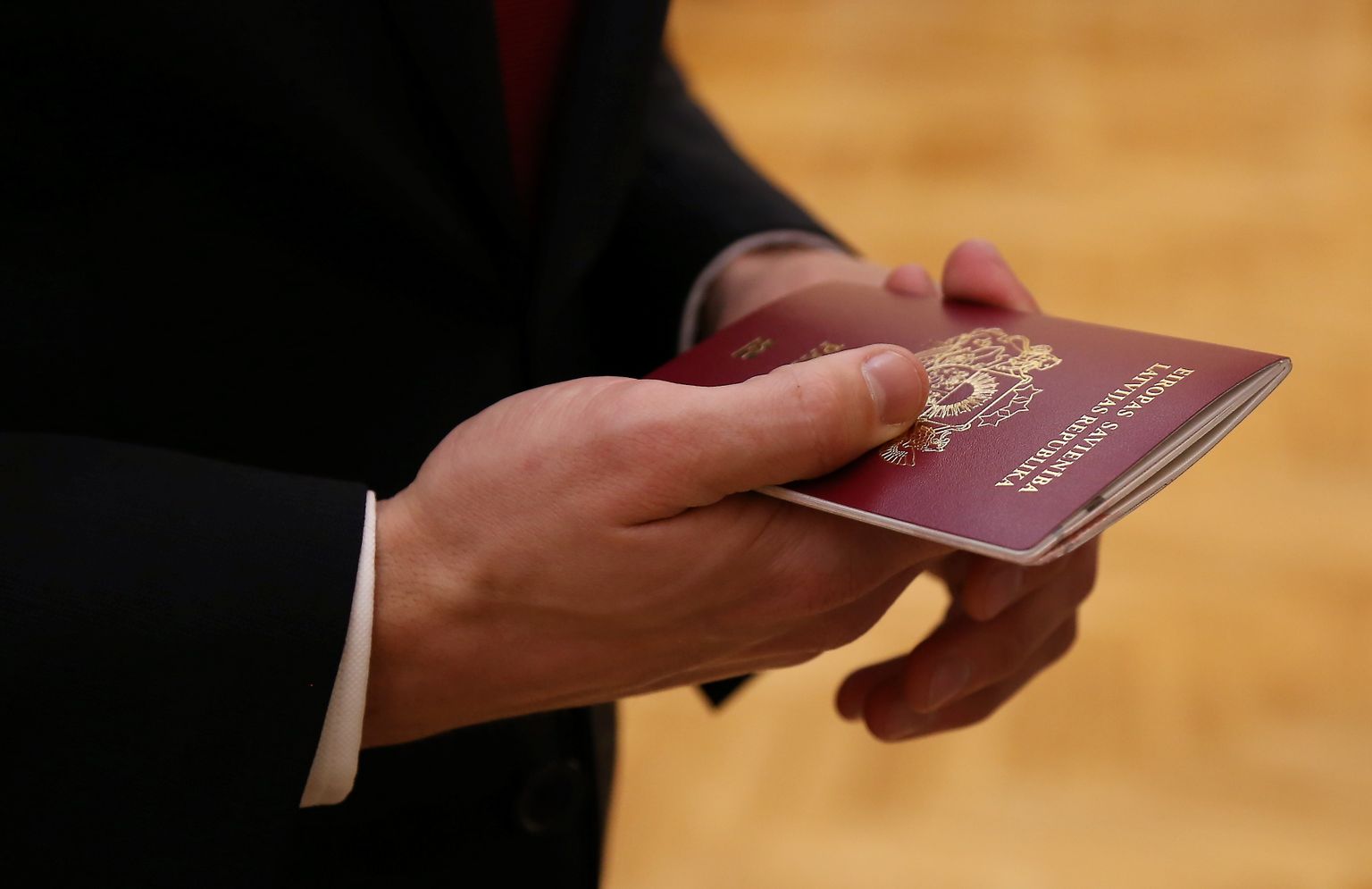 Человек держит в руках паспорт гражданина Латвии