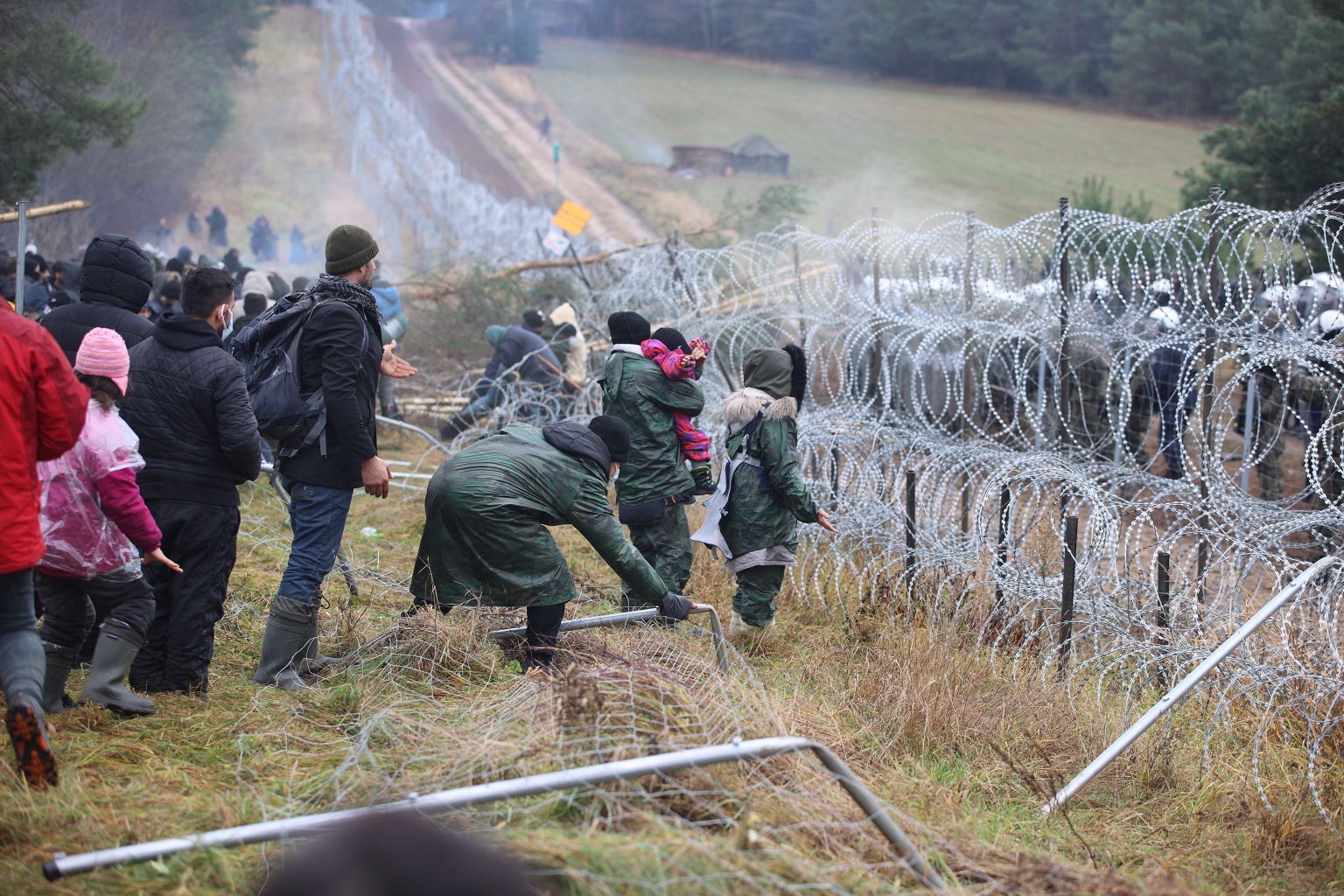 Migrandid Valgevene-Poola piiril. Paremal oksatraadi taga on näha Poola politseid ja sõdureid