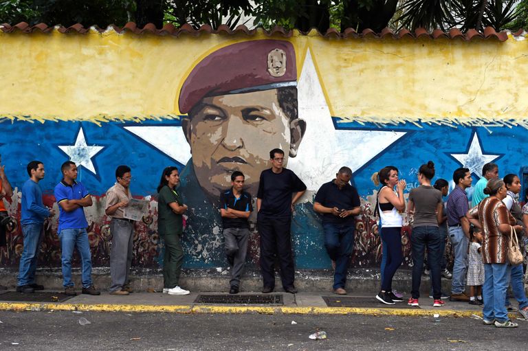 Venezuela rahvas ootamas valimisjaoskondadesse pääsemist. Taustal riigi pikaajalise liidri Hugo Chavezi pilt.