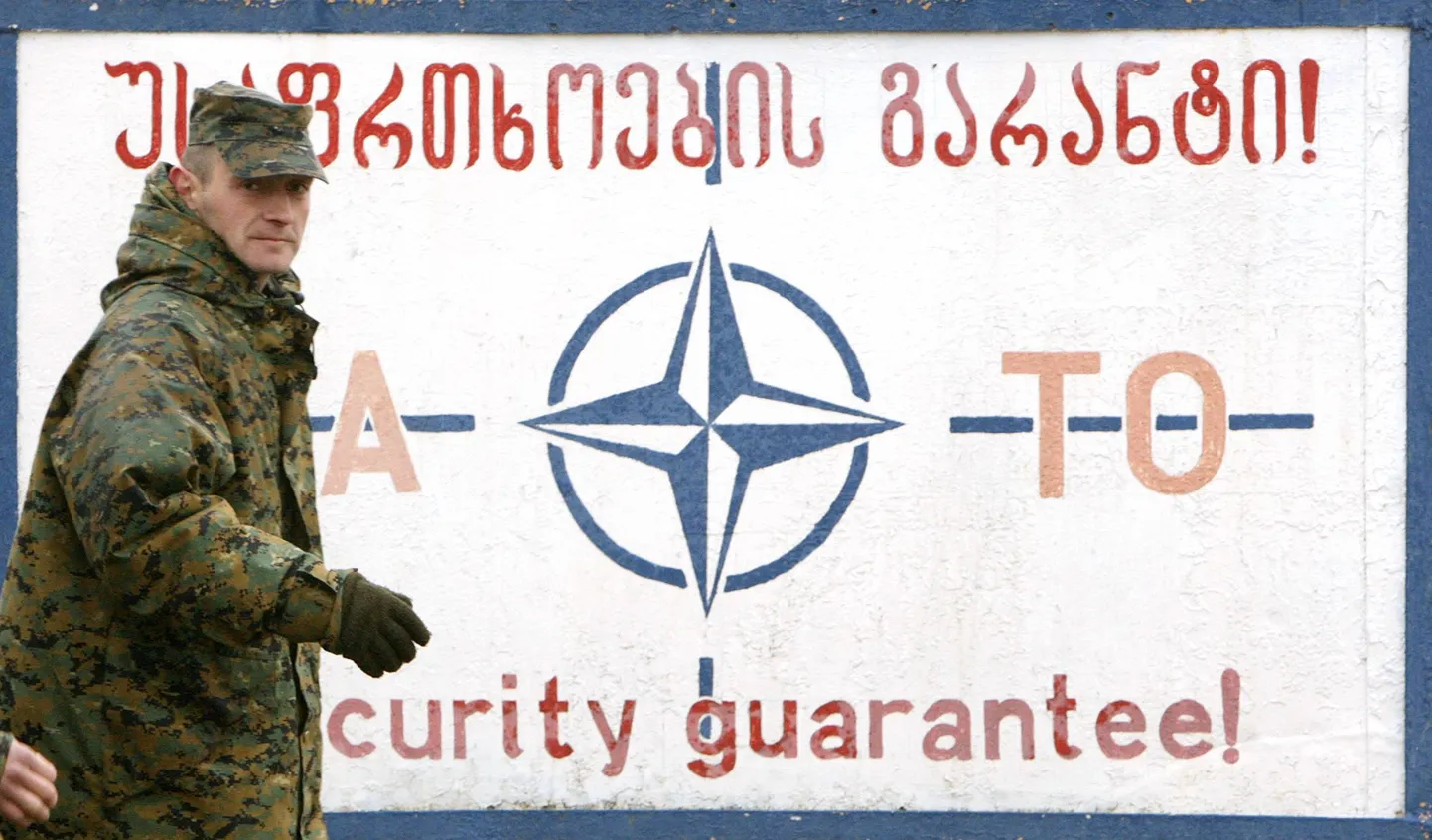 Gruusia sõdur möödumas NATO julgeolekugarantiid kuulutavast plakatist sõjaväebaasis Thbilisi lähjedal.