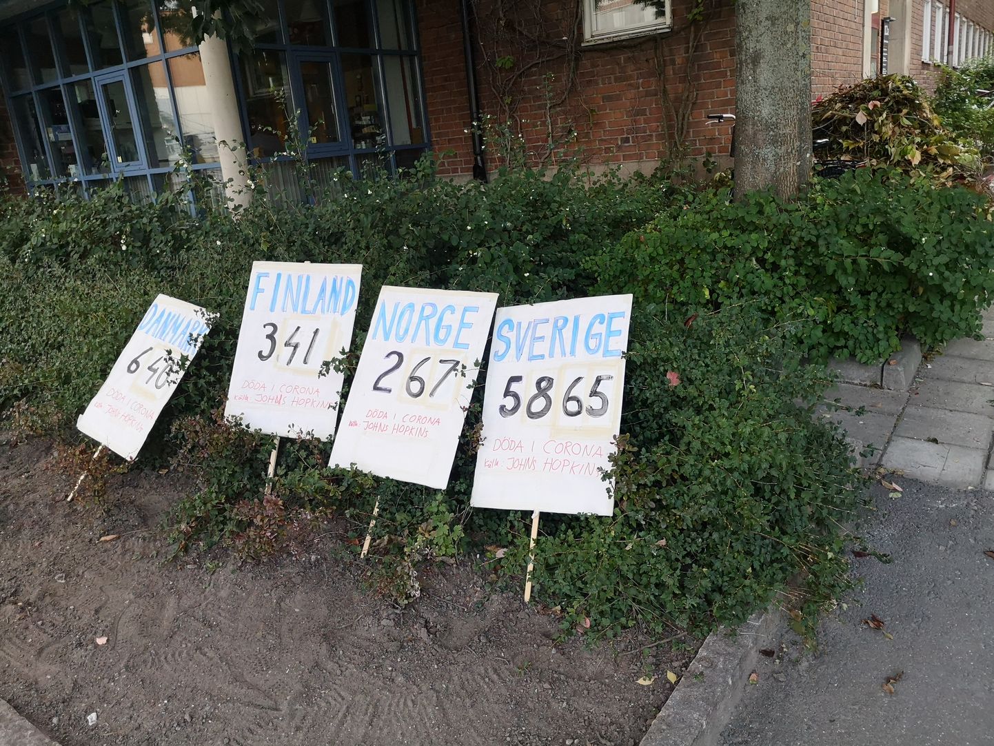 Meeleavaldajate plakatid Stockholmis rahvaterviseameti juures, millet on näha nukker statistika: Rootsis on Covid-19 tõttu surnud palju enam inimesi kui naaberriikides.