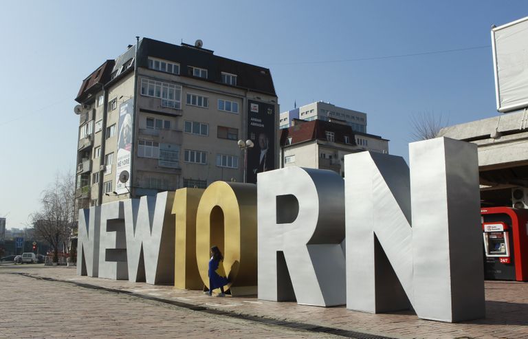 Kosovo lippu mähitud tüdruk riigi 10. sünnipäevaks püstitatud monumendo ees. 