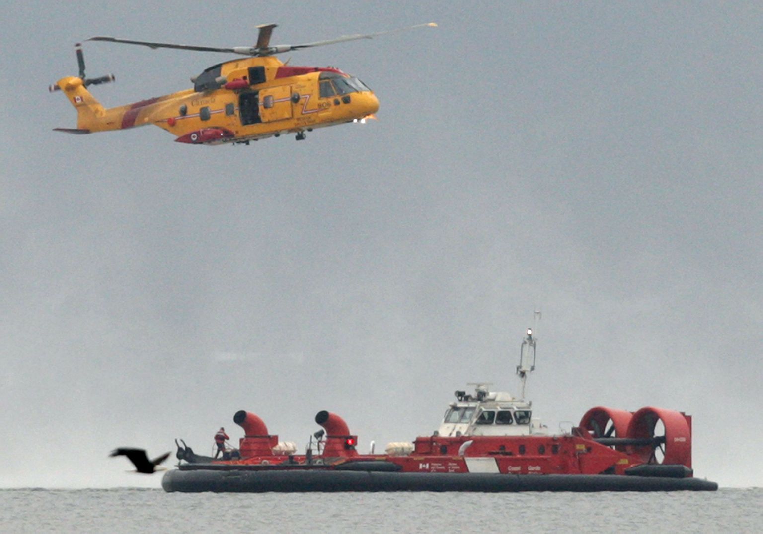 Kanada õhujõudude Cormorant-tüüpi helikopter ja rannavalve hõljuk otsimas merel kadunud inimesi.