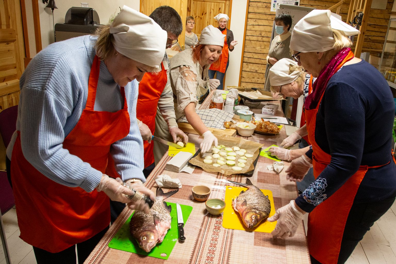 Esimesena võtsid kokandus- ja keelehuvilised ette Peipsi kala valmistamise. Esiplaanil toimetavad latikaga Jelena Bukina (vasakul) ja Laine Altmäe, nende kõrval lõiguvad sibulat Sergei Tumanov ja Natalja Tumanova, sibularattaid laob kalale padjaks Mari Oolberg.